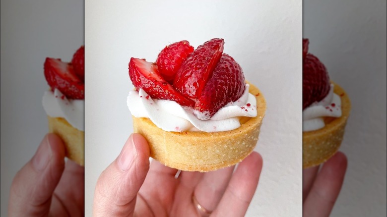 Holding strawberry tartlet