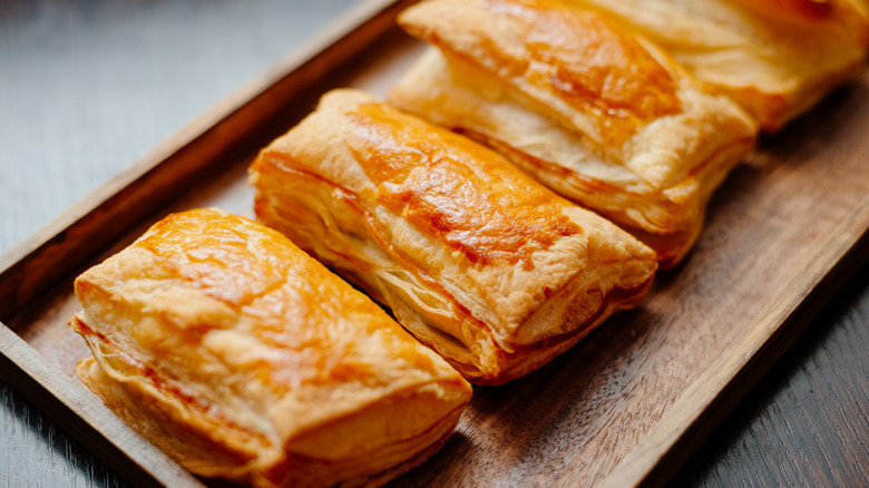 Baked puff pastry with toppings. Puffs with cheese on a wooden tray.