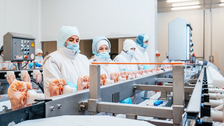 Masked workers in a chicken packing plant