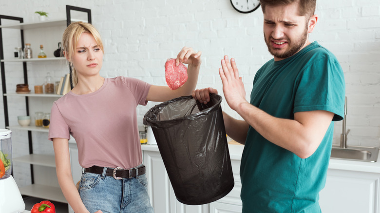 couple throwing bad meat away