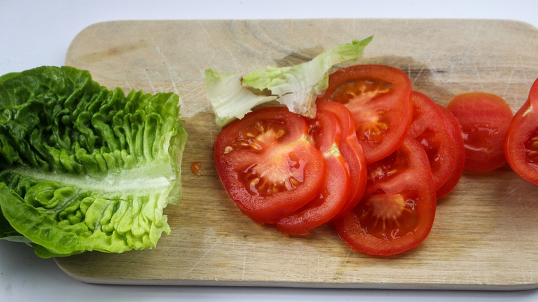 Lettuce and tomato on cutting board