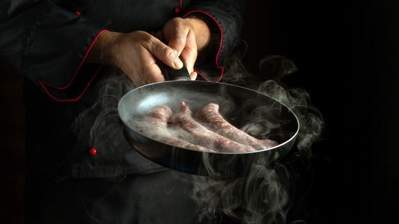 holding sausage in pan