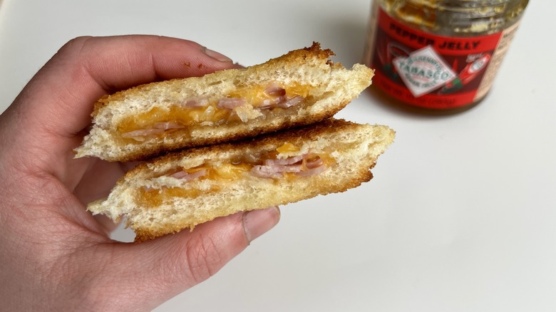 hand holding a circular, jelly-filled sandwich cut in half