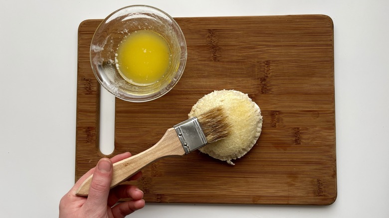 hand pressing a paintbrush onto a circular sandwich