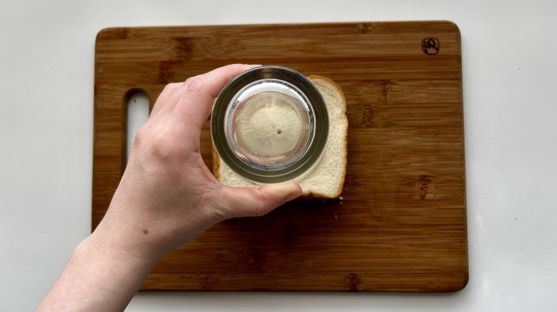 hand pressing a glass onto a sandwich