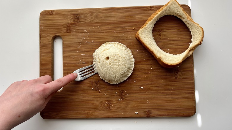 hand pressing a fork into a circular sandwich