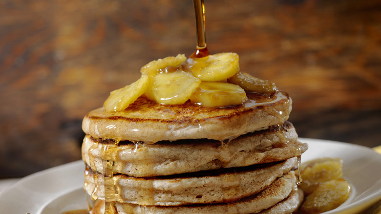 a stack of pancakes with maple syrup being poured on