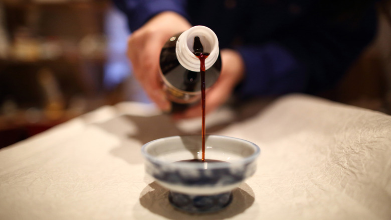 a waiter out of shot pours soy sauce into a bowl