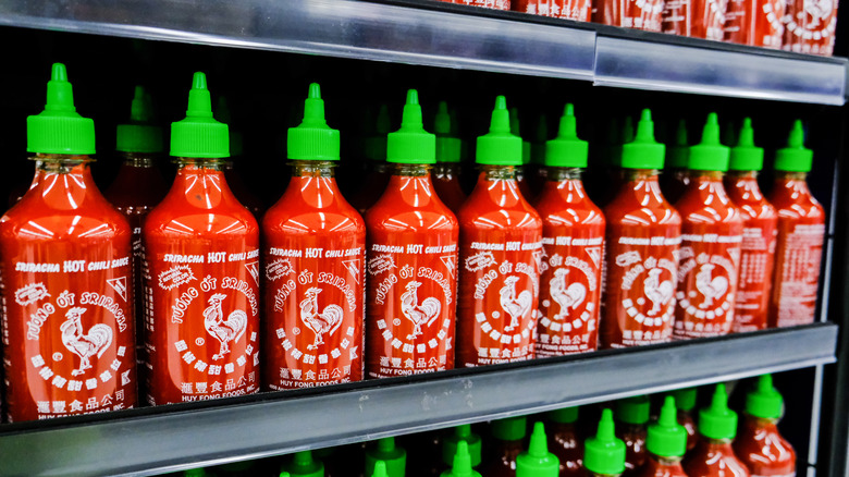 bottles of sriracha lining a shelf