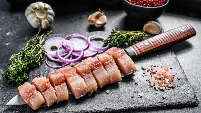 fillet of pickled herring on cutting board