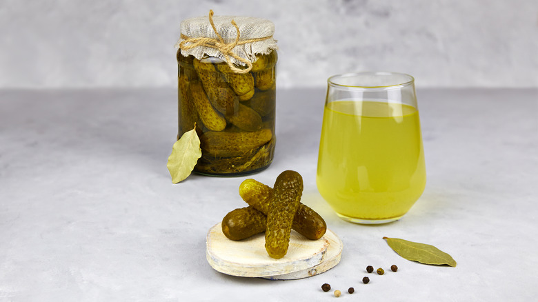 Glass of pickle brine and pickle jar