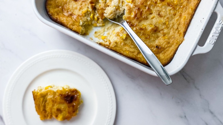 Corn pudding in casserole dish with piece on plate