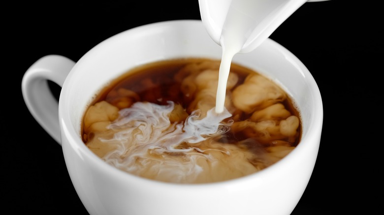 pouring creamer into coffee mug