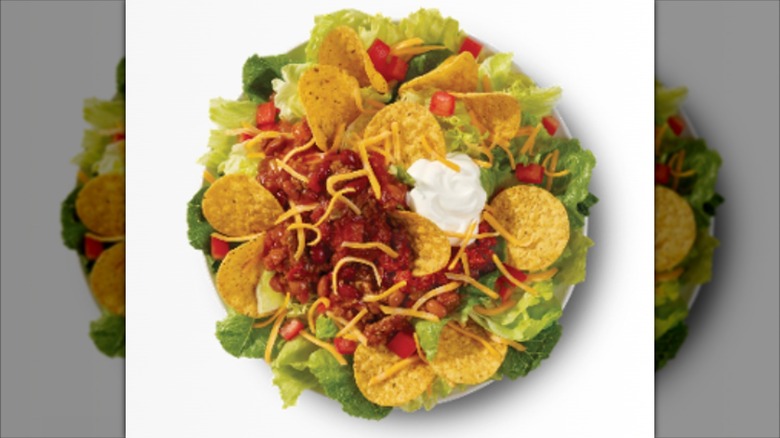 A taco salad from Wendy's has lettuce, cheese, chili, tortilla chips, and sour cream.