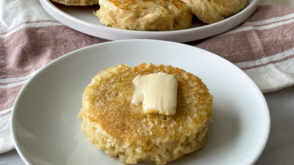 buttery crumpets on white plate with striped towel