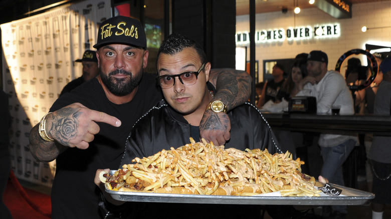 Locals holding a Fat Sal's sandwich covered in fries