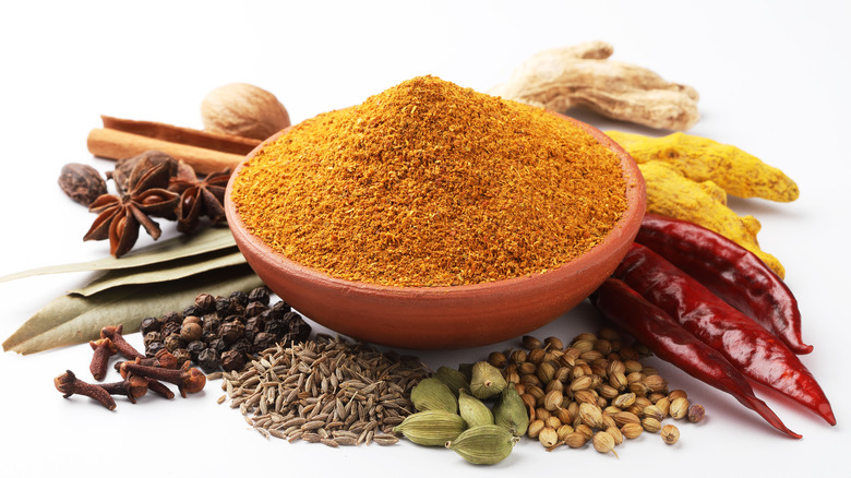 Bowl of garam masala surrounded by whole spices