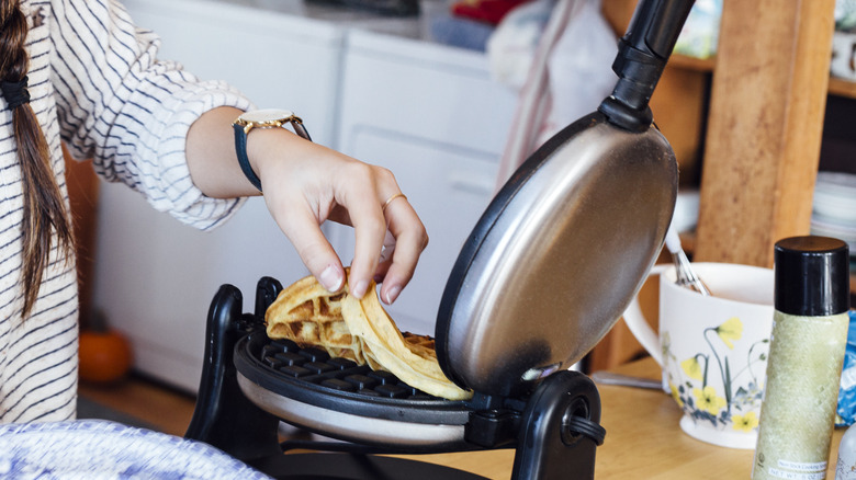 person pulling waffle out of iron