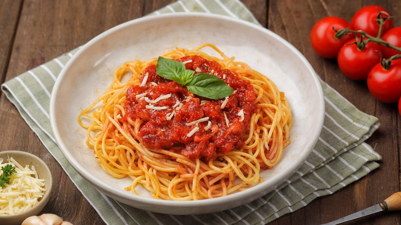 plate of spaghetti and marinara sauce garnished with parmesan cheese and basil