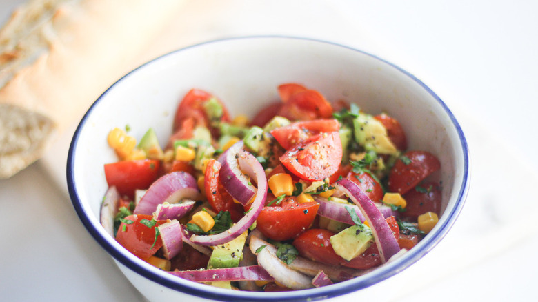 White bowl with salad of chopped onion, tomato, and avocado