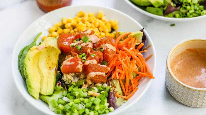 Marinated raw fish on salad of avocado, corn, and lettuce.