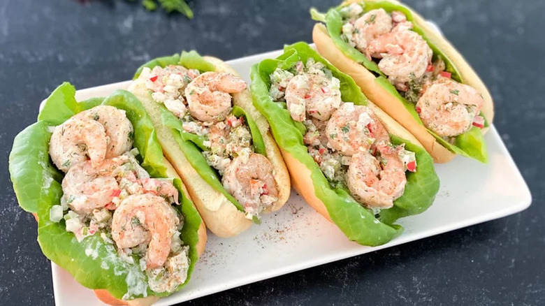 Whole shrimp salad with lettuce in top-split long buns.