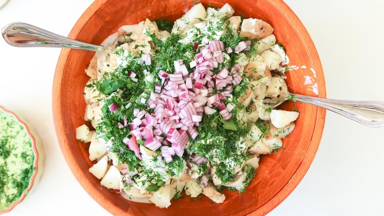Wooden bowl with diced potatoes, dill, and red onion