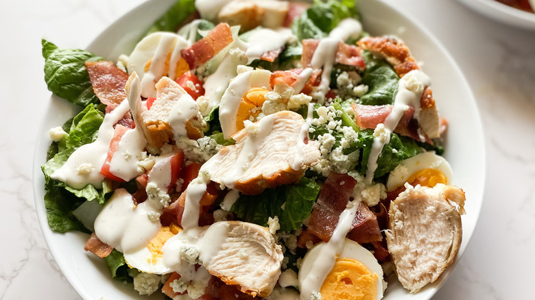 Salad with chicken, egg, bacon, and drizzle of dressing