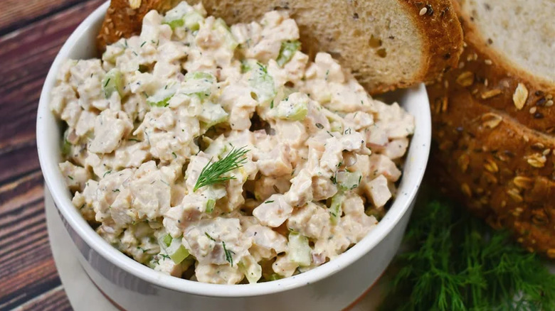 Bowl of chopped turkey salad with a slice of seeded bread