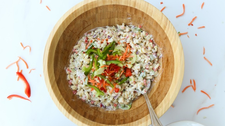 Wooden bowl of macaroni salad topped with peppers