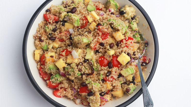 Bowl of cooked quinoa with mango and tomato chunks