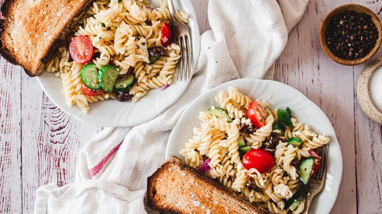 Plates of rotini pasta salad with toast. 