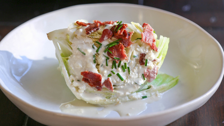 Wedge of iceberg lettuce with creamy dressing and bacon