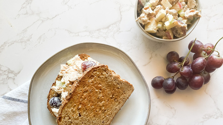 Chicken salad with grapes in a bowl and a sandwich.