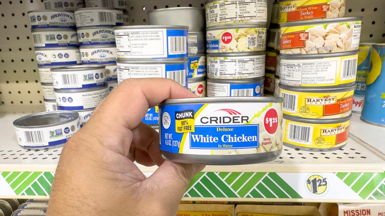 Person holding canned chicken in the store