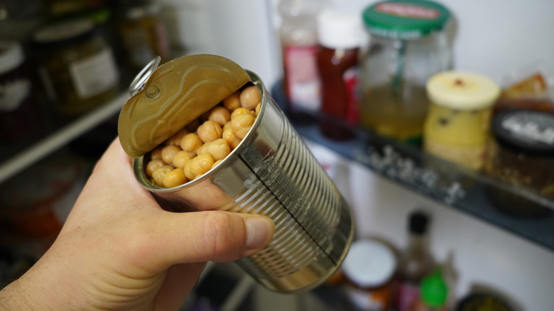 Person holding can of chickpeas in pantry