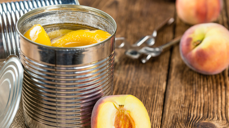 Can of peaches next to fresh peaches