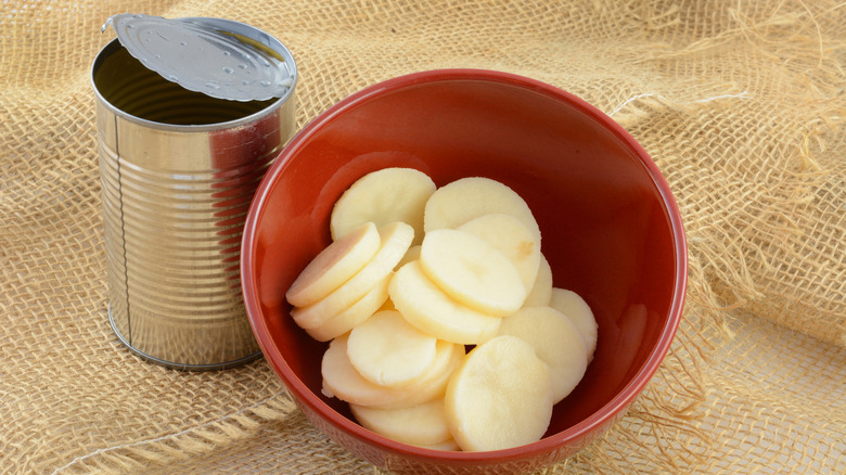 Sliced potatoes in a bowl next to a can