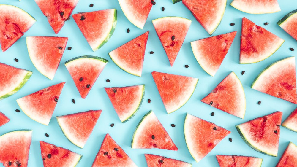 slices of watermelon and watermelon seeds scattered on a blue background