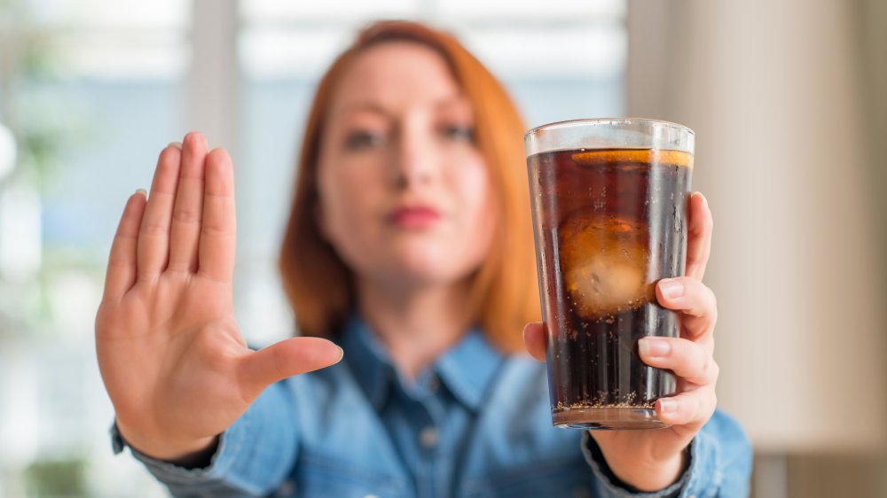 woman holding a soda and using her hand as a stop sign