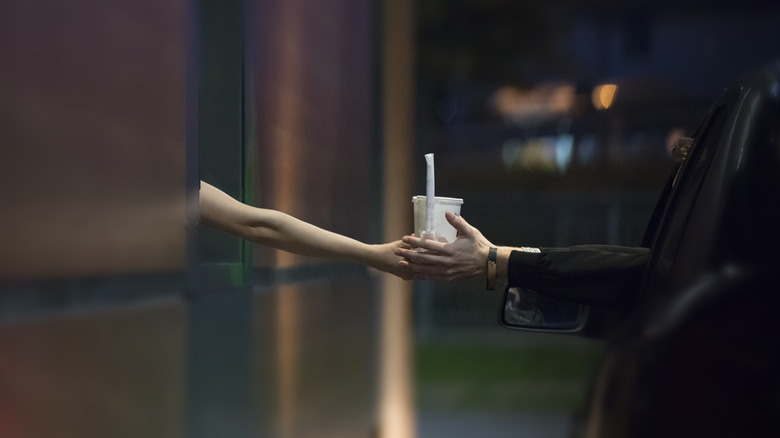 Employee handing customer a drink at drive-thru