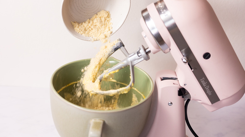 adding flour mixture to bowl of stand mixer