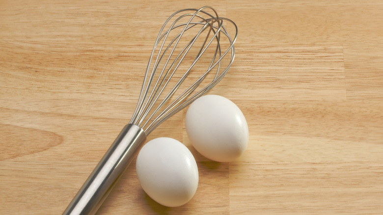 Wire whisk with two white eggs