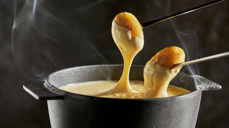 Fondue forks being dipped into cheese fondue