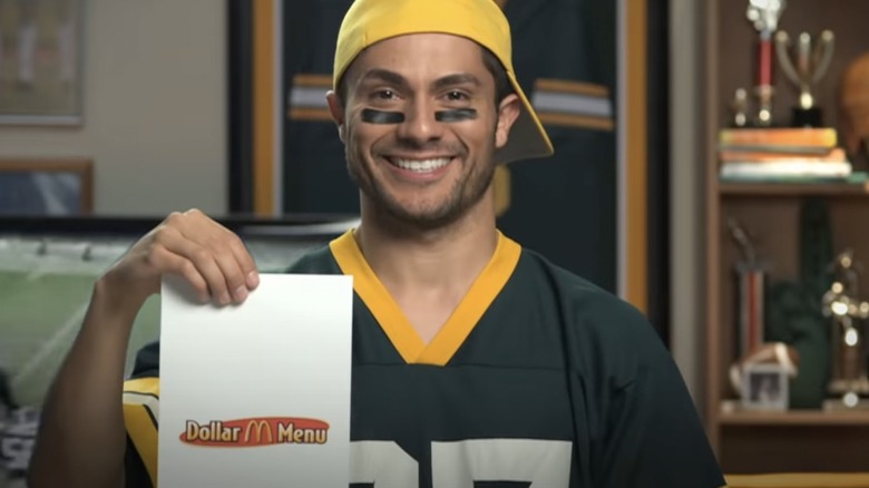 Man in football jersey holding McDonald's Dollar Menu bag in ad