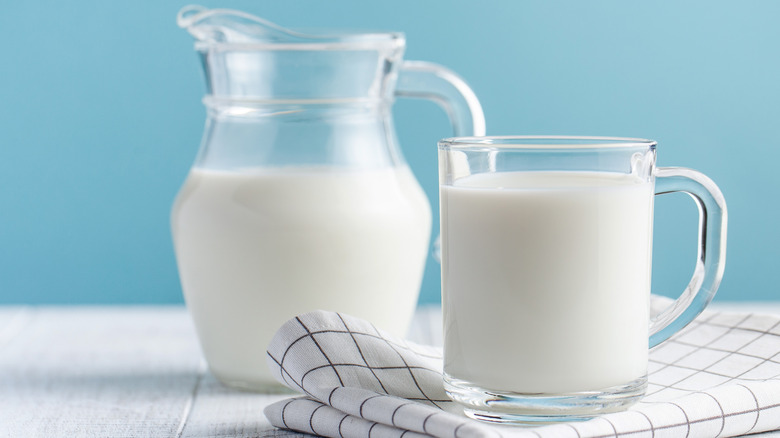 Pitcher and glass of milk on blue background