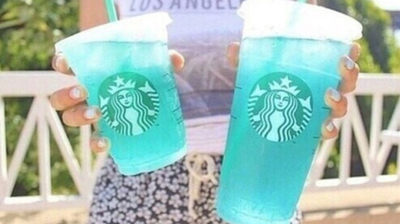 Girl holding two blue drinks from Starbucks