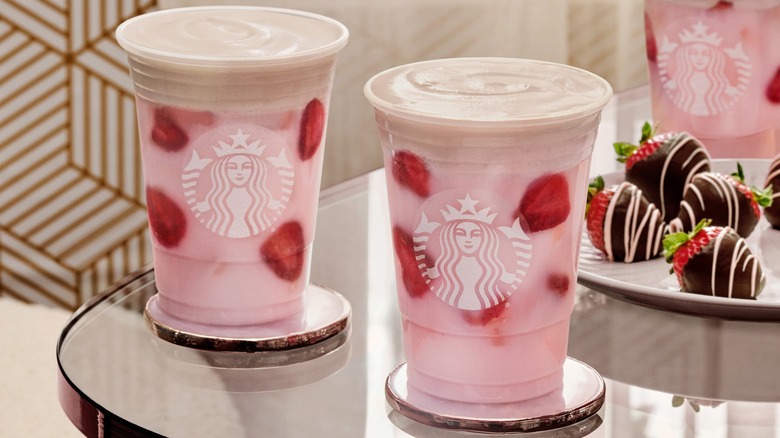 Two starbucks strawberry drinks next to chocolate covered strawberries