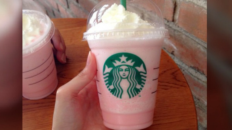 Person holding a pink frappuccino from Starbucks