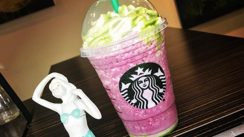 Starbucks mermaid Frappuccino next to a toy mermaid